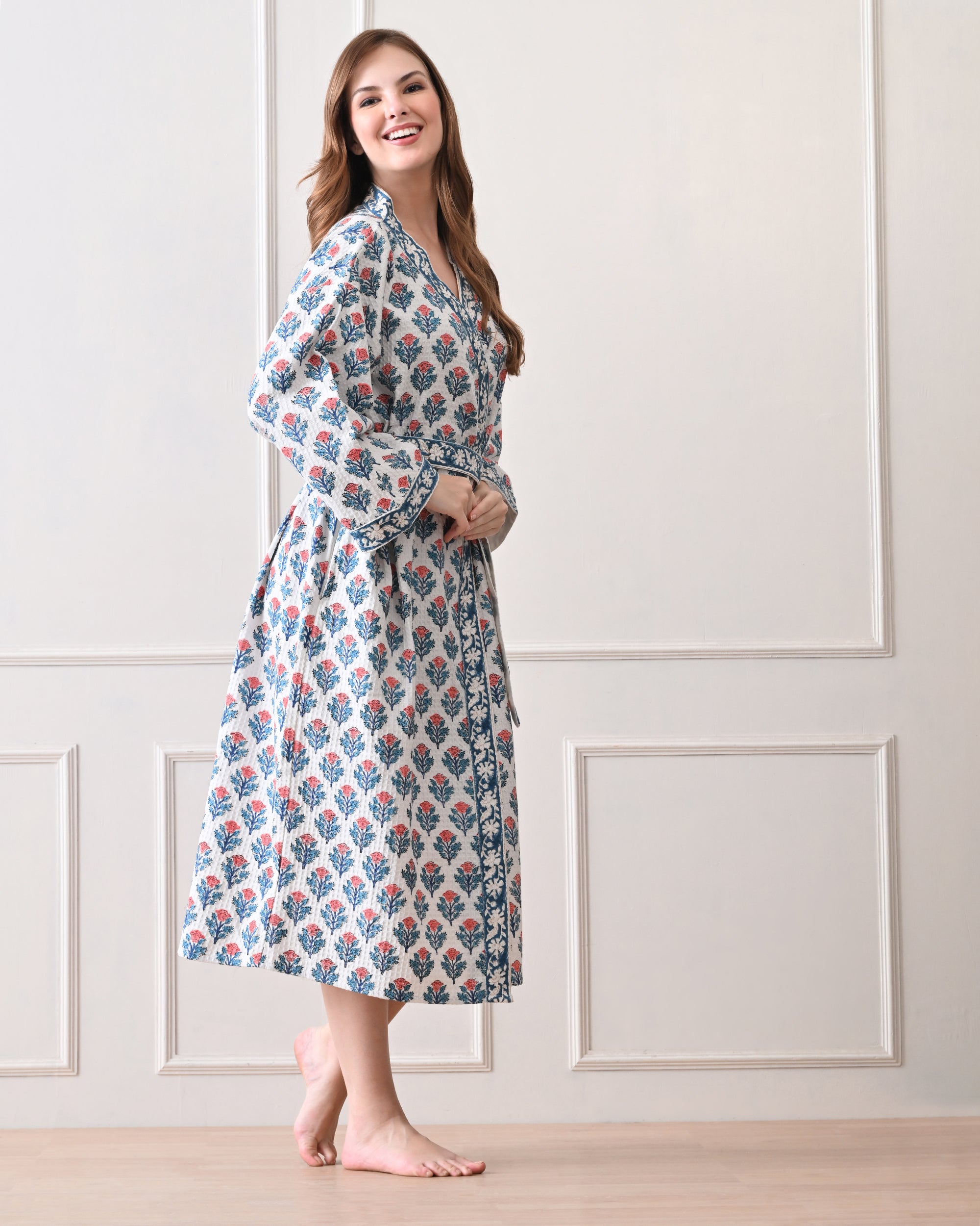 Tropic Blush Blue Cotton Waffle Bathrobe with hand block printed blue and pink floral patterns, blue floral border, long sleeves, and waist tie belt, worn by a woman | Singhvis