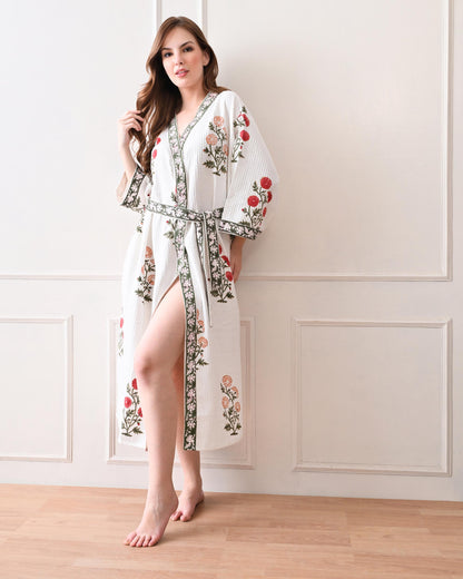 Meadow Light White Cotton Waffle Bathrobe with hand block printed floral patterns in red and orange, green leaves and green floral border, long sleeves, and waist tie belt, worn by a woman | Singhvis 
