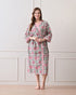 Drifting Garden Pink & Green Cotton Bathrobe with hand block printed pink garden flowers with green leaf patterns on a white base, pink border, long sleeves, and waist tie belt, worn by a woman | Singhvis 