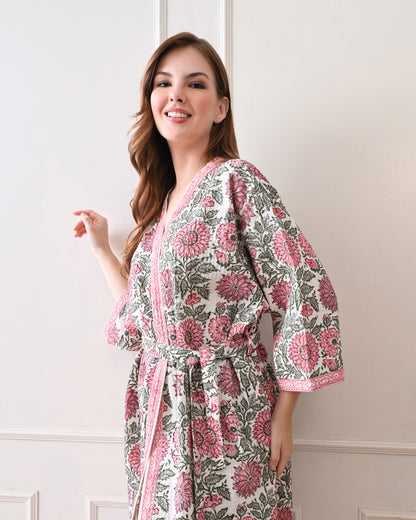 Drifting Garden Pink &amp; Green Cotton Bathrobe with hand block printed pink garden flowers with green leaf patterns on a white base, pink border, long sleeves, and waist tie belt, worn by a woman | Singhvis 