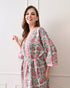 Drifting Garden Pink & Green Cotton Bathrobe with hand block printed pink garden flowers with green leaf patterns on a white base, pink border, long sleeves, and waist tie belt, worn by a woman | Singhvis 
