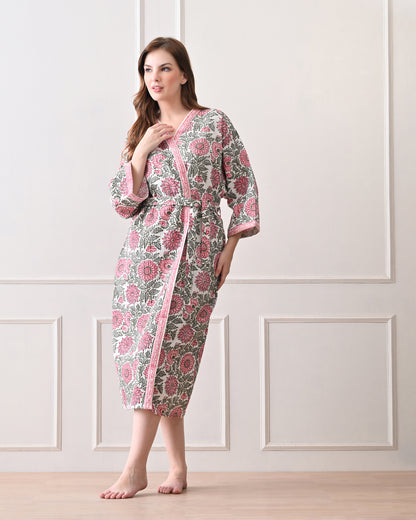 Drifting Garden Pink &amp; Green Cotton Bathrobe with hand block printed pink garden flowers with green leaf patterns on a white base, pink border, long sleeves, and waist tie belt, worn by a woman | Singhvis 