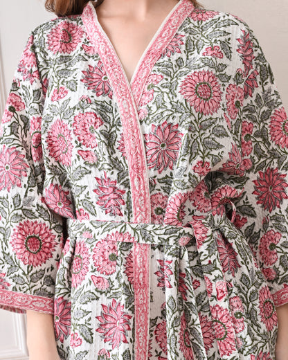 Drifting Garden Pink &amp; Green Cotton Bathrobe with hand block printed pink garden flowers with green leaf patterns on a white base, pink border, long sleeves, and waist tie belt, worn by a woman | Singhvis 