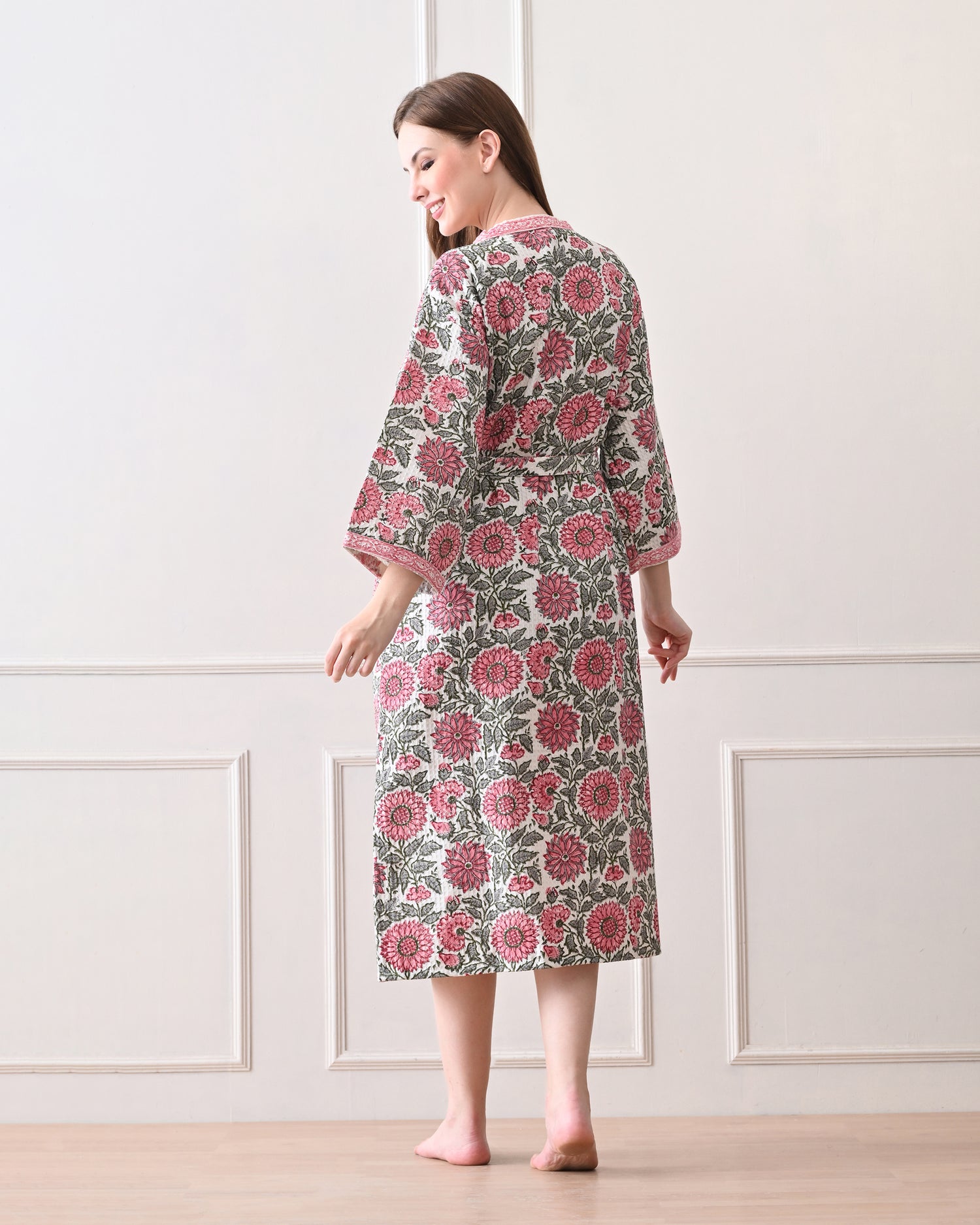Drifting Garden Pink &amp; Green Cotton Bathrobe with hand block printed pink garden flowers with green leaf patterns on a white base, pink border, long sleeves, and waist tie belt, worn by a woman | Singhvis 