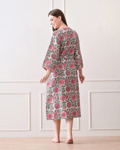 Drifting Garden Pink &amp; Green Cotton Bathrobe with hand block printed pink garden flowers with green leaf patterns on a white base, pink border, long sleeves, and waist tie belt, worn by a woman | Singhvis 