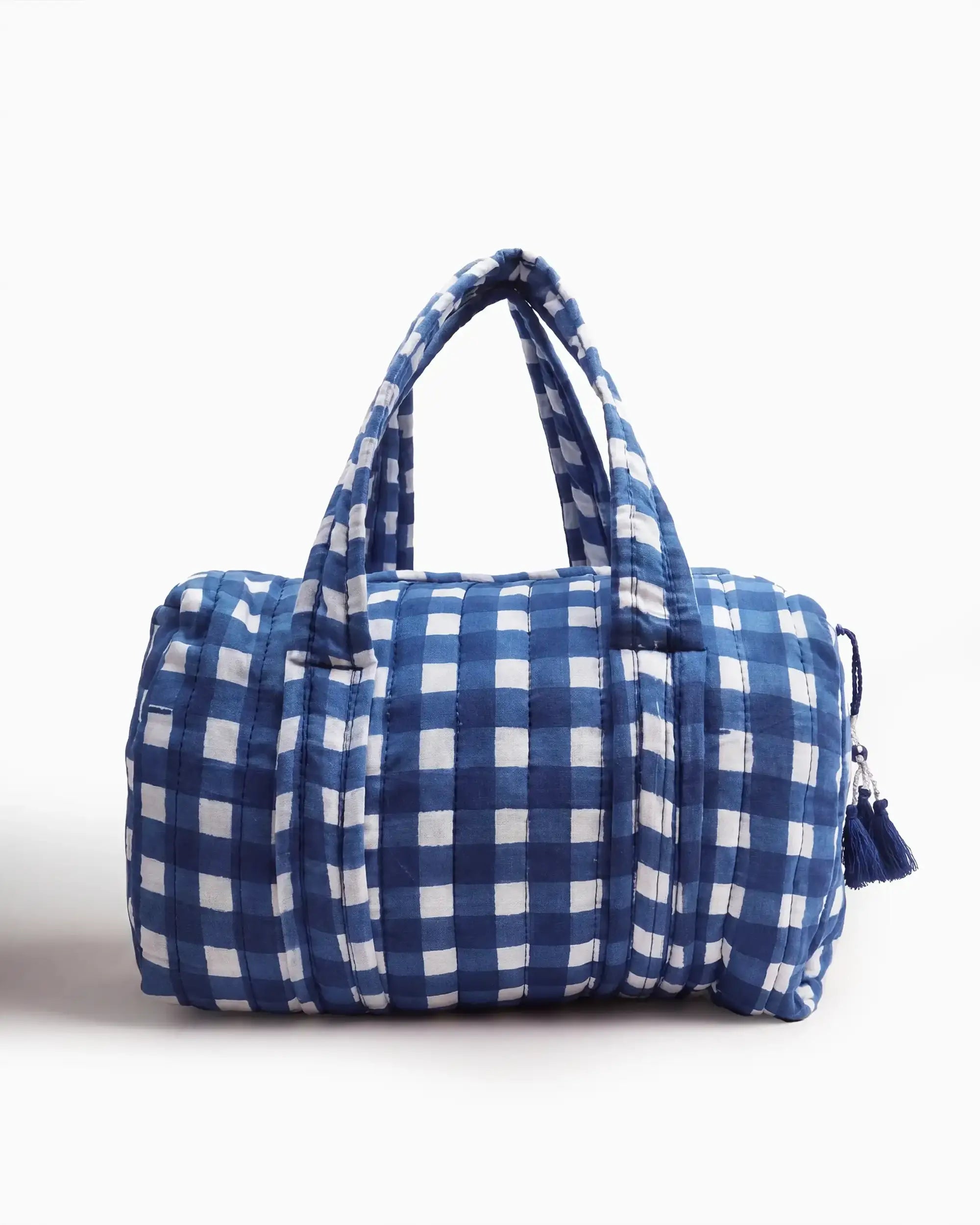 Blue gingham vanity bag with quilted texture and soft handles, featuring a side zipper with a tassel placed on a plain white background | Singhvis