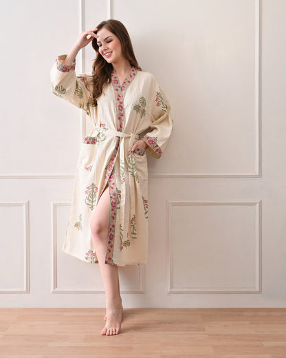  Island Flora White Cotton Waffle Bathrobe with hand block printed floral design, pink border, long sleeves, waist tie belt, worn by a woman | Singhvis