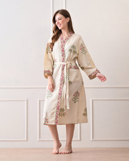  Island Flora White Cotton Waffle Bathrobe with hand block printed floral design, pink border, long sleeves, waist tie belt, worn by a woman | Singhvis