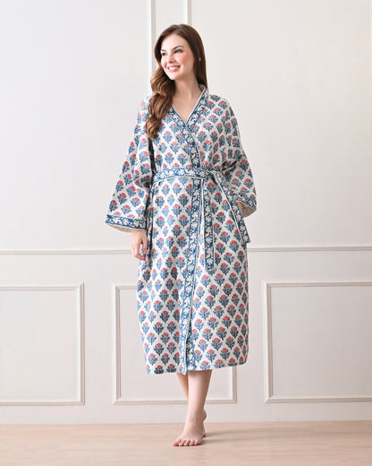 Tropic Blush Blue Cotton Waffle Bathrobe with hand block printed blue and pink floral patterns, blue floral border, long sleeves, and waist tie belt, worn by a woman | Singhvis 