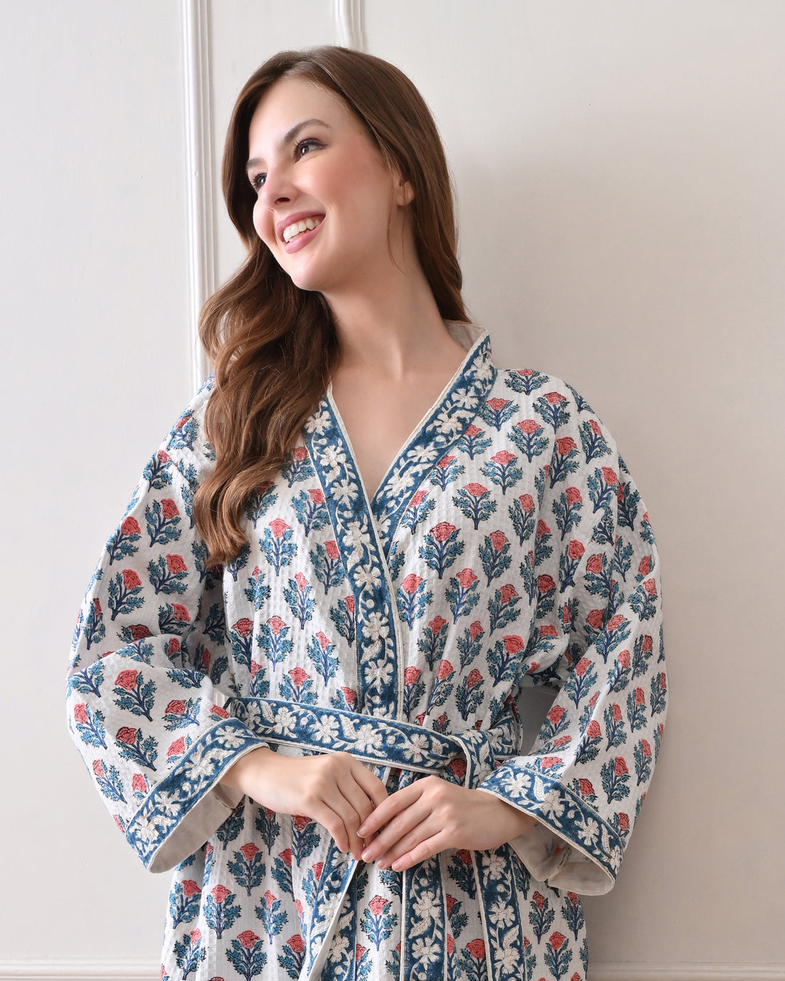 Tropic Blush Blue Cotton Waffle Bathrobe with hand block printed blue and pink floral patterns, blue floral border, long sleeves, and waist tie belt, worn by a woman | Singhvis 