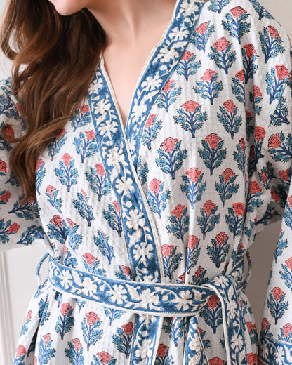 Tropic Blush Blue Cotton Waffle Bathrobe with hand block printed blue and pink floral patterns, blue floral border, long sleeves, and waist tie belt, worn by a woman | Singhvis 